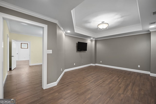 empty room featuring ornamental molding, a tray ceiling, and dark hardwood / wood-style floors