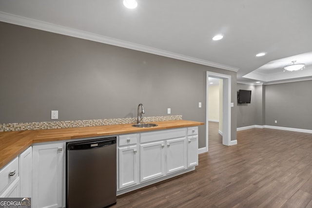 kitchen with butcher block countertops, white cabinets, ornamental molding, and sink