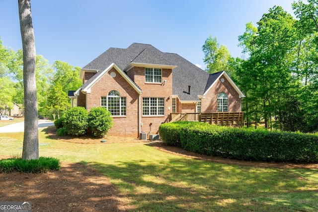 front of property with cooling unit, a wooden deck, and a front lawn