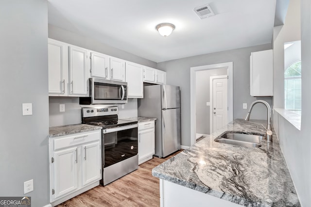 kitchen featuring light wood-type flooring, appliances with stainless steel finishes, white cabinetry, and sink