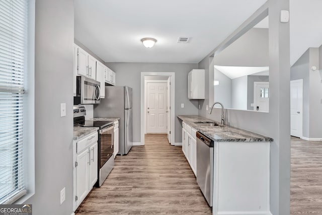 kitchen with white cabinetry, light stone counters, stainless steel appliances, and sink