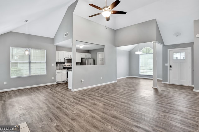 unfurnished living room with high vaulted ceiling, ceiling fan, wood-type flooring, and ornate columns