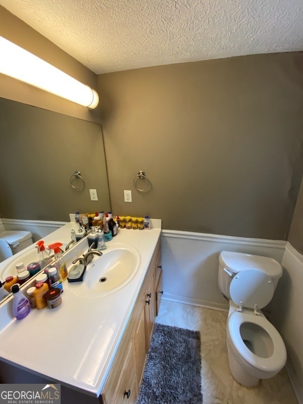 bathroom with vanity, a textured ceiling, and toilet