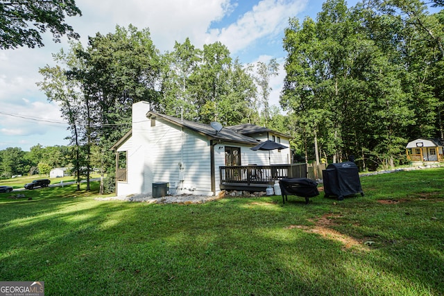 rear view of house featuring a lawn and a deck