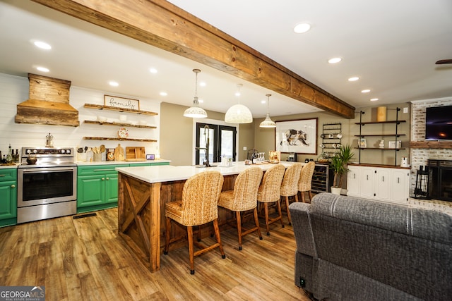 kitchen featuring green cabinets, custom range hood, a brick fireplace, stainless steel electric stove, and a kitchen breakfast bar