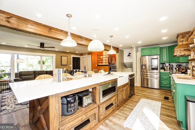 kitchen with green cabinets, light hardwood / wood-style flooring, appliances with stainless steel finishes, ceiling fan, and pendant lighting