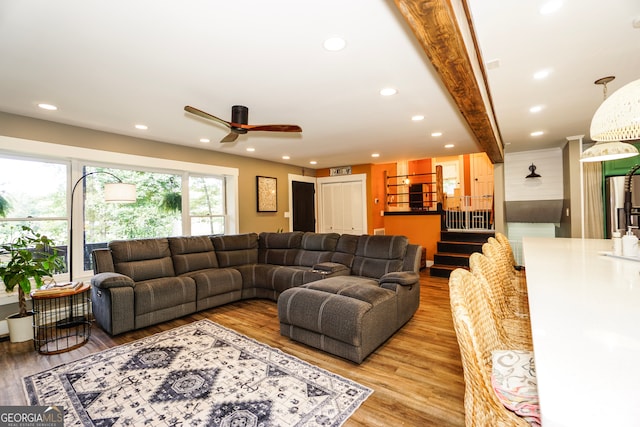 living room with ceiling fan, beamed ceiling, and hardwood / wood-style floors