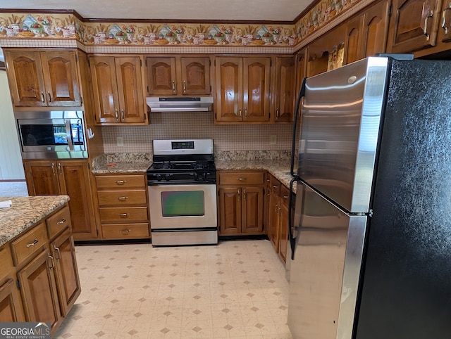 kitchen featuring backsplash, light stone counters, and stainless steel appliances