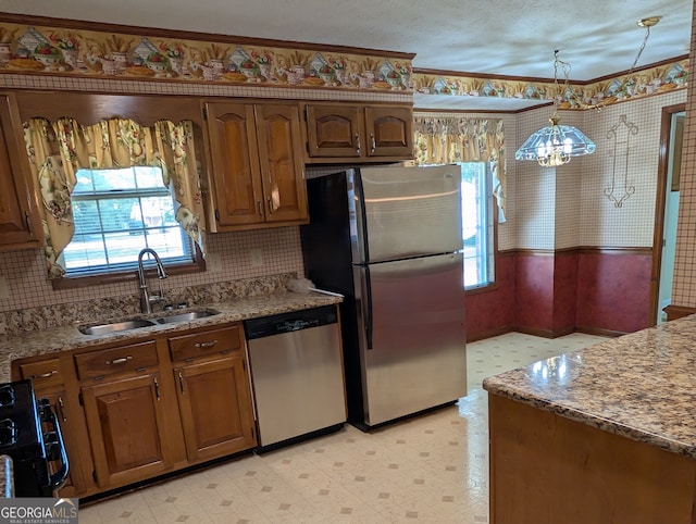 kitchen with pendant lighting, a textured ceiling, a chandelier, sink, and appliances with stainless steel finishes