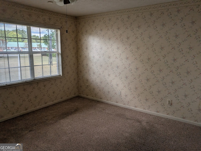 carpeted empty room with ceiling fan and a textured ceiling