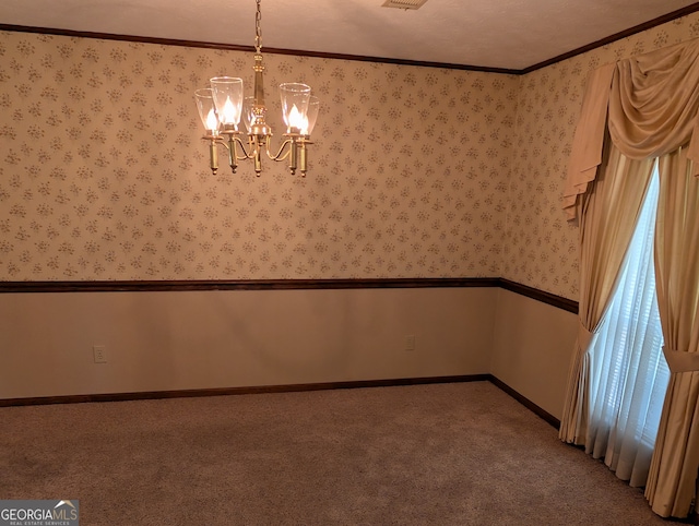 carpeted spare room featuring ornamental molding and a notable chandelier