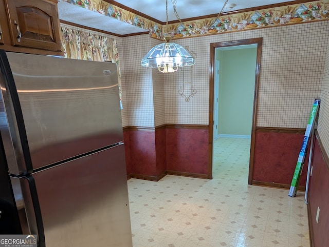 kitchen featuring crown molding, pendant lighting, an inviting chandelier, and stainless steel fridge