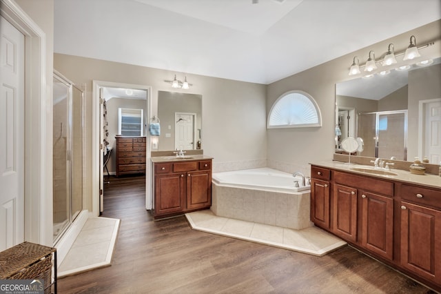 bathroom with plus walk in shower, hardwood / wood-style floors, lofted ceiling, and vanity