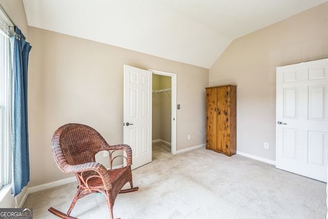 living area with light colored carpet, vaulted ceiling, and a healthy amount of sunlight