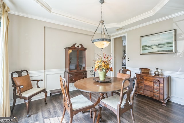 dining room with dark wood-type flooring, ornamental molding, and a raised ceiling