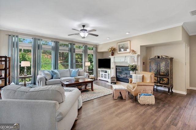 living room with crown molding, dark wood-type flooring, and ceiling fan