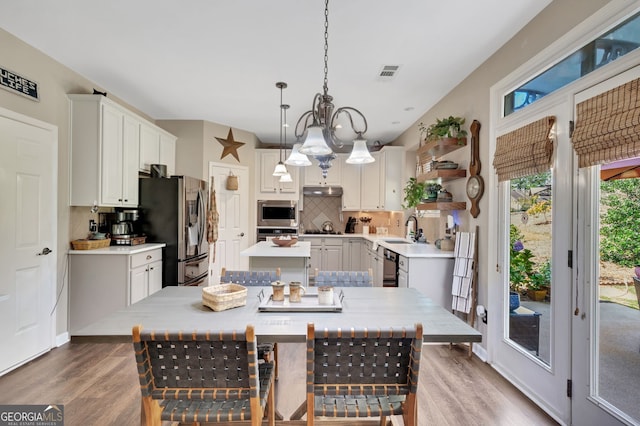 kitchen featuring appliances with stainless steel finishes, hardwood / wood-style floors, decorative light fixtures, and a center island