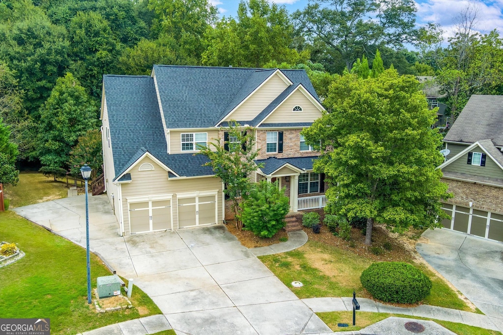 view of front of home featuring a garage, roof with shingles, concrete driveway, and a front yard