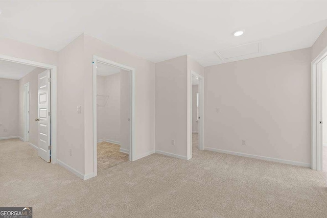 unfurnished bedroom featuring a spacious closet, light carpet, and a closet