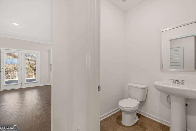 bathroom featuring hardwood / wood-style floors, crown molding, and toilet