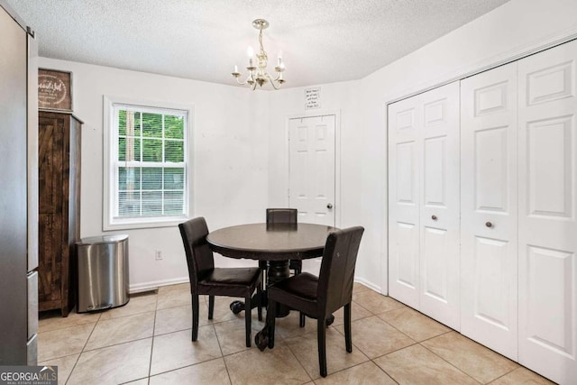 tiled dining room featuring an inviting chandelier and a textured ceiling