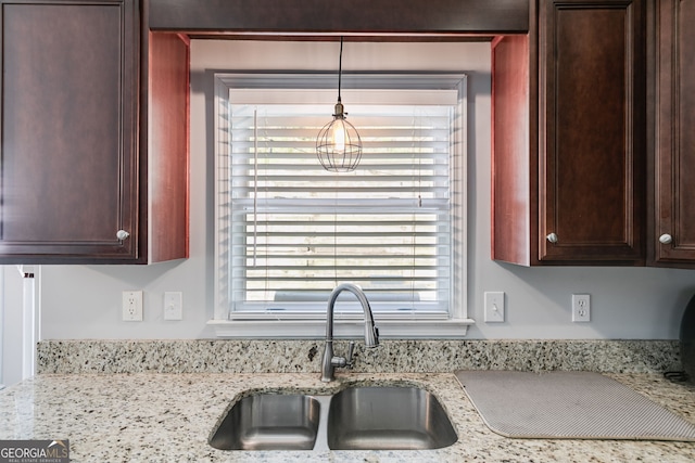 kitchen featuring light stone counters, decorative light fixtures, and sink