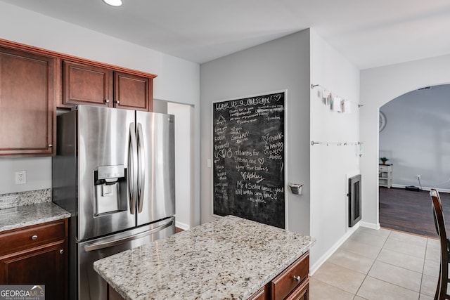 kitchen featuring stainless steel fridge with ice dispenser, light stone counters, and light hardwood / wood-style flooring