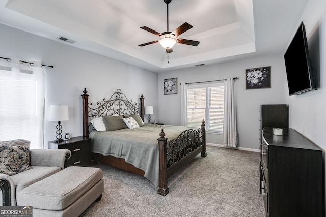 carpeted bedroom featuring a tray ceiling and ceiling fan