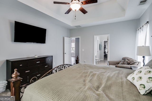 bedroom featuring carpet flooring, a tray ceiling, ceiling fan, and ensuite bathroom