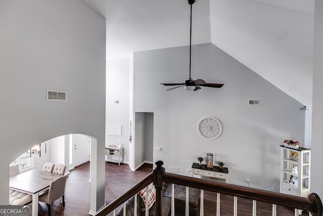 corridor with a notable chandelier, dark wood-type flooring, and high vaulted ceiling