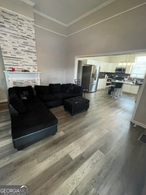 living room with a large fireplace, crown molding, and wood-type flooring