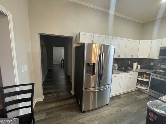 kitchen with light stone countertops, dark hardwood / wood-style flooring, appliances with stainless steel finishes, crown molding, and white cabinetry