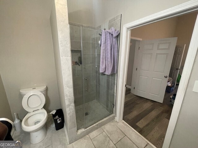 bathroom with toilet, hardwood / wood-style flooring, and an enclosed shower