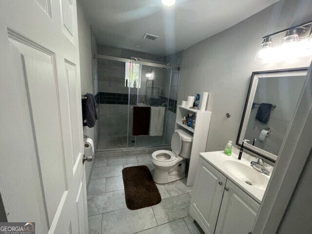 bathroom with vanity, toilet, tile patterned flooring, and a shower with door