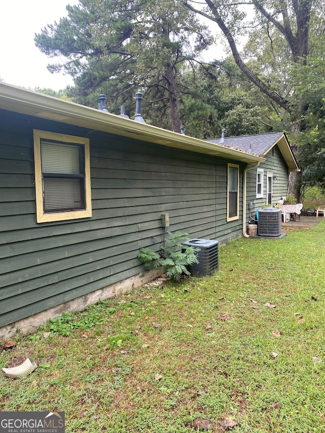 view of home's exterior with cooling unit and a lawn