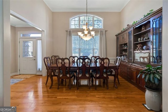 dining space with crown molding, light wood finished floors, and a chandelier