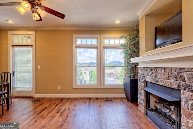 living room with ceiling fan, ornamental molding, hardwood / wood-style flooring, and a fireplace