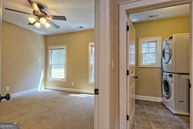 washroom featuring ceiling fan, dark colored carpet, and stacked washer and dryer