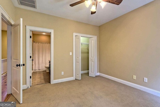 unfurnished bedroom with light colored carpet, connected bathroom, a closet, and ceiling fan