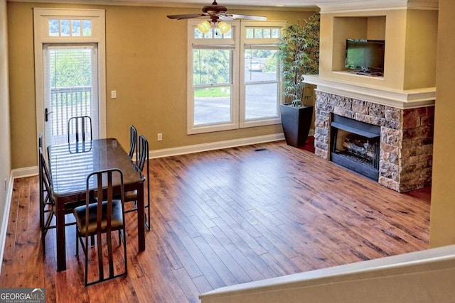 dining room with wood-type flooring, ceiling fan, a fireplace, and plenty of natural light