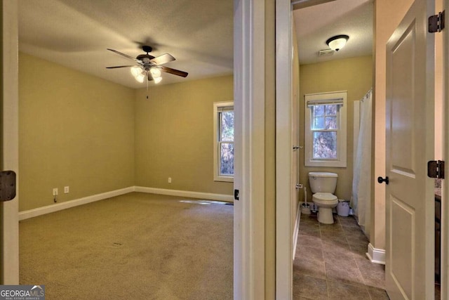 interior space featuring ceiling fan and toilet