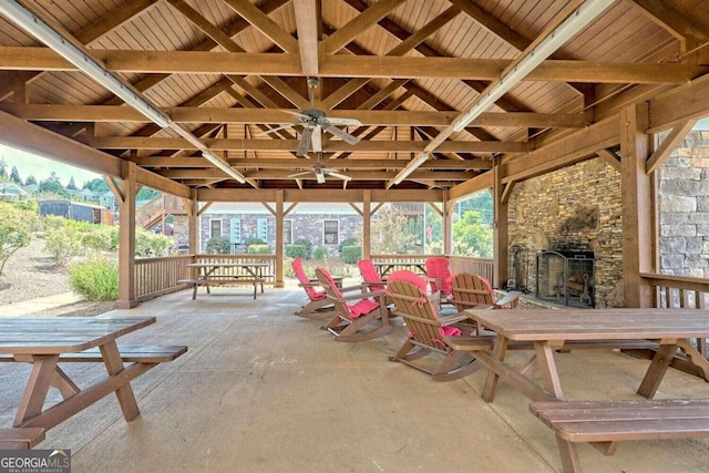 view of patio with an outdoor stone fireplace and ceiling fan