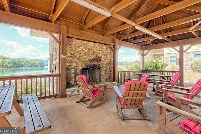 view of patio with an outdoor stone fireplace and a water view