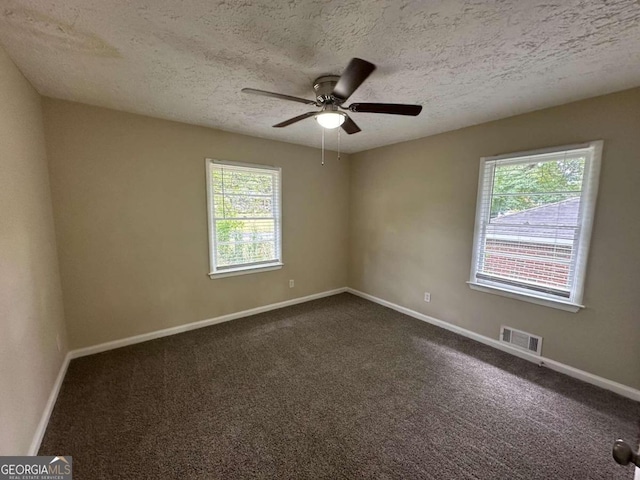 carpeted spare room with a textured ceiling, a wealth of natural light, and ceiling fan