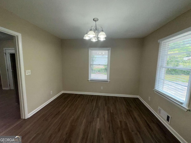 spare room with dark hardwood / wood-style flooring and a notable chandelier