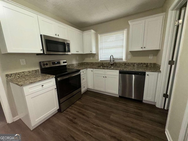 kitchen featuring dark stone countertops, dark wood-type flooring, white cabinetry, and stainless steel appliances