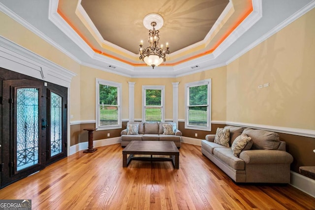 living room with ornamental molding, a chandelier, a tray ceiling, and hardwood / wood-style flooring