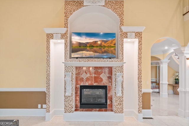 room details with ornamental molding, a tiled fireplace, decorative columns, and tile patterned flooring