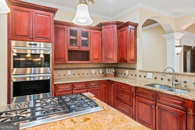 kitchen with hanging light fixtures, backsplash, stainless steel appliances, ornate columns, and sink