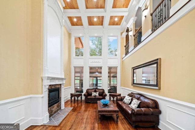 living room with coffered ceiling, a high end fireplace, crown molding, beam ceiling, and hardwood / wood-style flooring